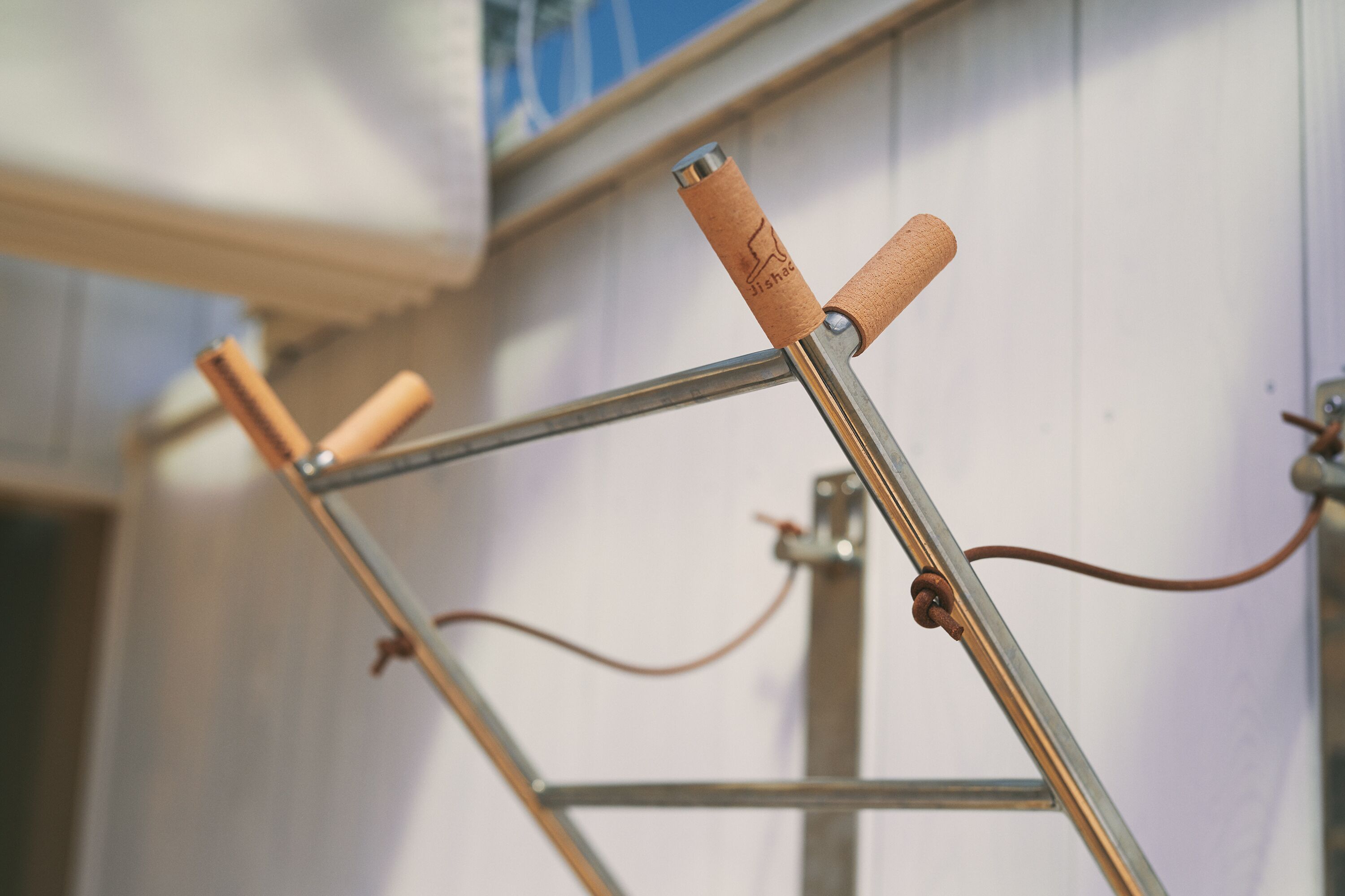 A metal ladder with wooden steps and a metal handrail, leaning against a white wall.
