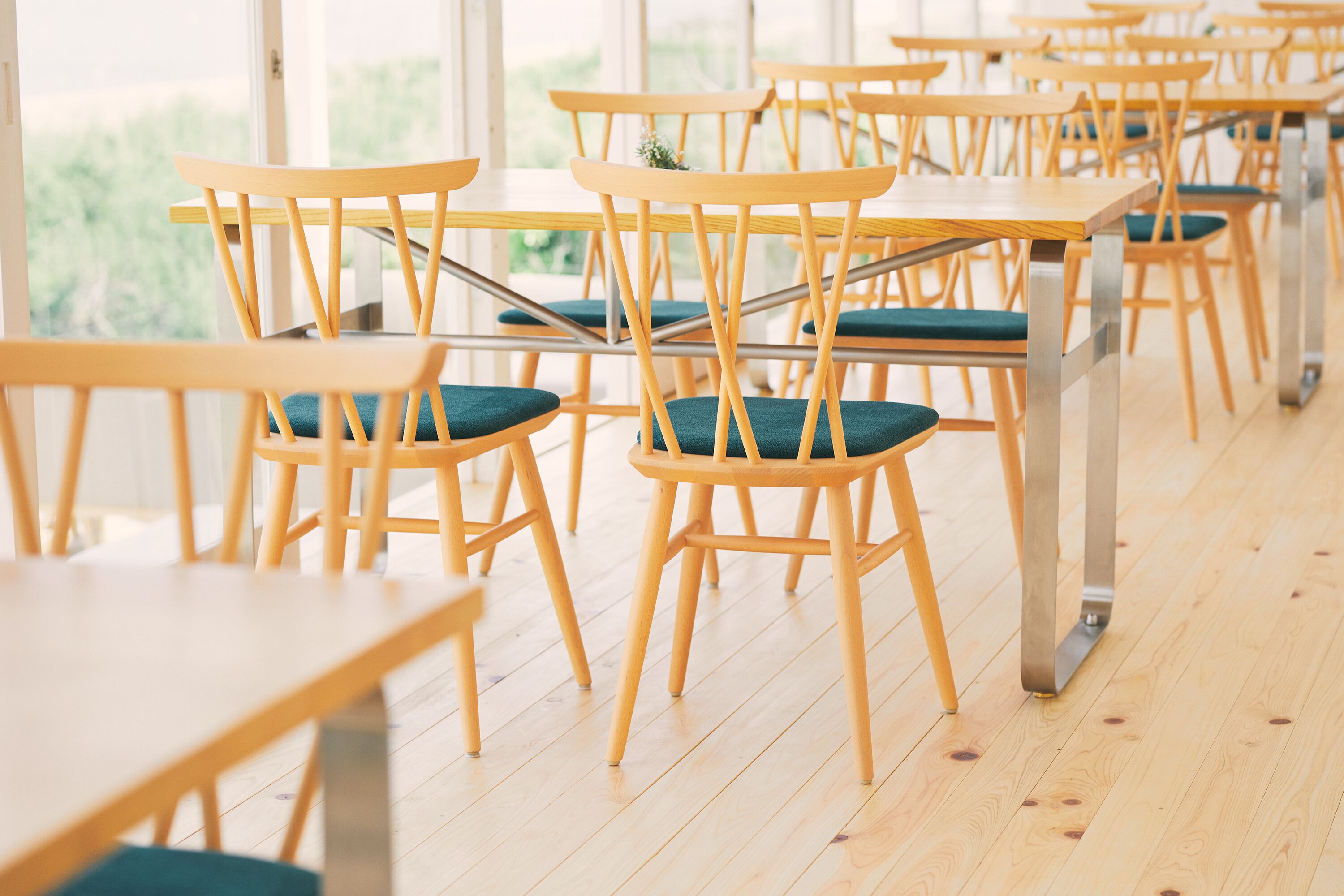 A classroom with wooden tables and chairs, arranged in rows.