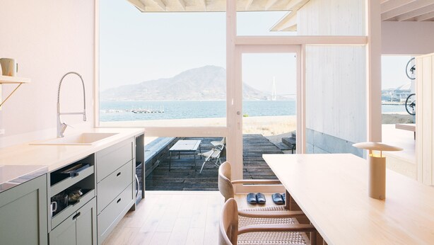 Una cocina moderna con un ventanal grande que da a una terraza y al mar.