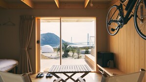 Una habitación con piso de madera, una cama, una mesa y una bicicleta colgada en la pared.
