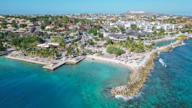 An aerial view of a coastal resort with a beach, clear turquoise waters, and a rocky shoreline. - Villa in Jan Thiel With Private Pool (Jan Thiel)