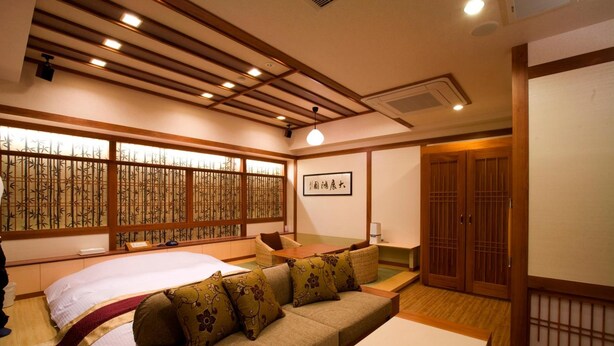 A traditional Japanese-style room with tatami flooring, a low wooden table, a sofa with cushions, and sliding doors. - Hotel Bintang Pari Resort - Adults Only (Kobe)