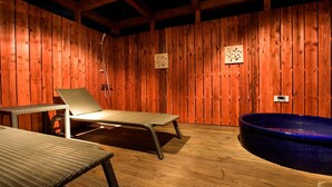 A wooden-floored room with a large blue bathtub, two lounge chairs, and a wooden wall with two small decorative panels. - Hotel Bintang Pari Resort - Adults Only (Kobe)
