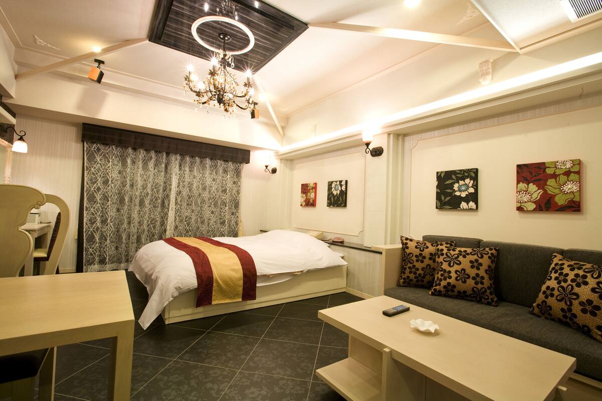 A modern hotel room with a bed, sofa, and a desk.