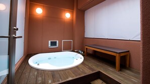 A spa room with a hot tub, wooden bench, and two wall-mounted lights. - Hotel Bintang Pari Resort - Adults Only (Kobe)