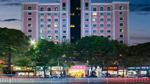 Un hotel grande de varios pisos con una entrada central y múltiples balcones.