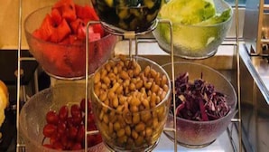 Un bufé con diversos alimentos, entre ellos sandía, aceitunas, ensalada verde y frijoles.