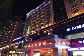 A multi-story building with illuminated signage, indicating various businesses on the ground floor.