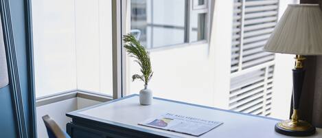 Un escritorio con una lámpara, una planta pequeña y un periódico.