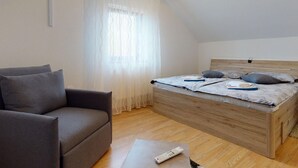 Ein Schlafzimmer mit einem hölzernen Bett, einem grauen Sofa und einer Fernbedienung auf einem kleinen Tisch.