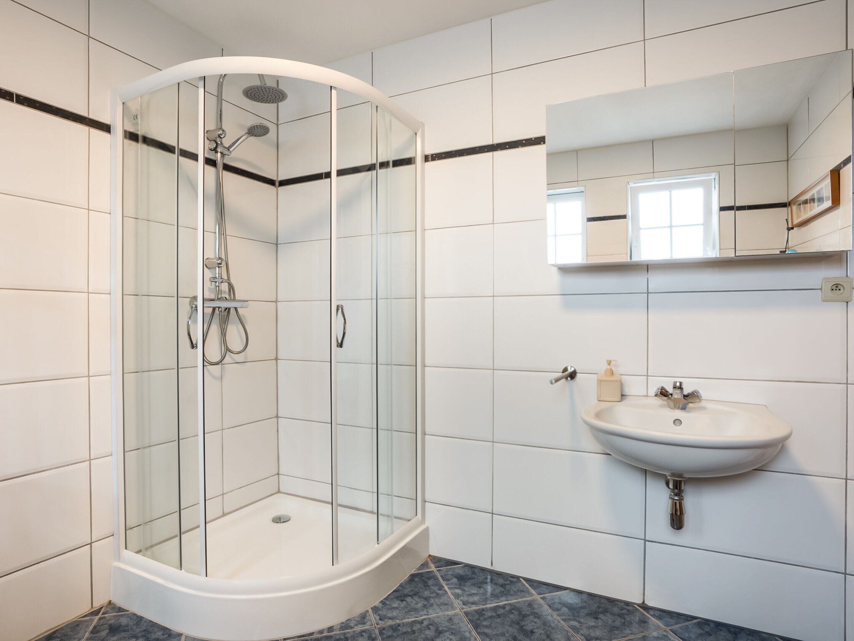 Une salle de bain moderne avec une douche à parois de verre, un lavabo et un miroir.