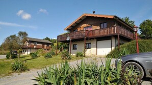 Ein zweigeschossiges Haus mit einem Balkon, einer Satellitenschüssel und einem geparkten Auto davor.