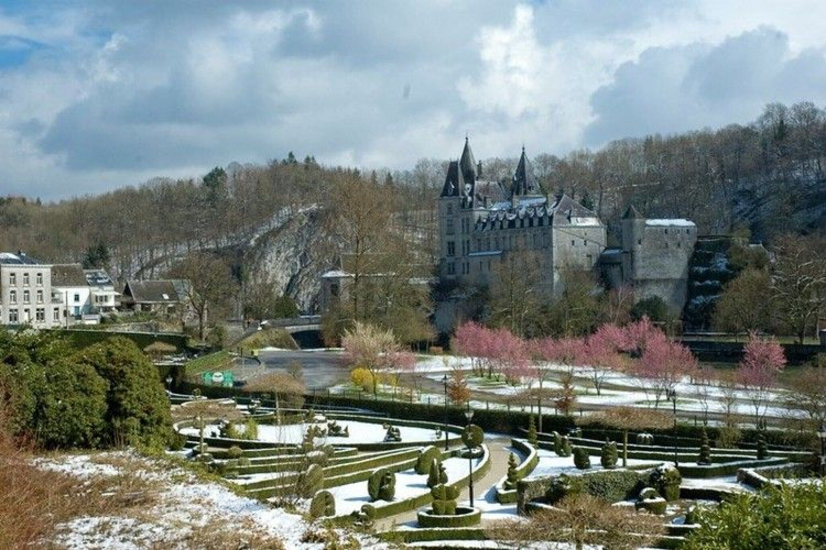 Een kasteel met een grote tuin, met geometrische hagen en een besneeerd landschap.