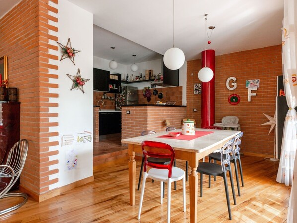 Une cuisine moderne avec un mur d’accent en briques, une table à manger en bois et des chaises rouges.