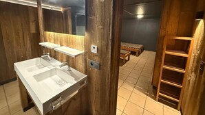 Un baño moderno con paneles de madera, un espejo grande, un lavamanos blanco y una repisa.