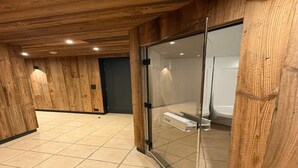 Un baño moderno con paneles de madera, cabina de ducha de vidrio y suelo de baldosas.
