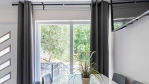 A modern dining area with a long table, black chairs, and a potted plant. - Soothing Holiday Home in Starigrad near Sea (Starigrad)