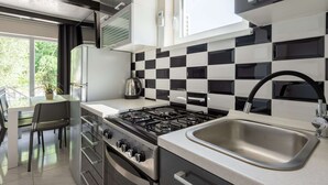 A modern kitchen with a gas stove, stainless steel sink, and black and white checkered backsplash. - Soothing Holiday Home in Starigrad near Sea (Starigrad)