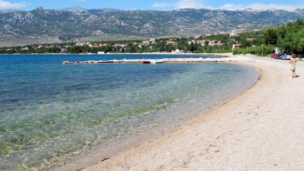 A beach with clear water, a sandy shore, and a backdrop of mountains. - Soothing Holiday Home in Starigrad near Sea (Starigrad)