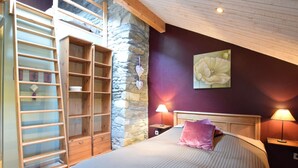 A bedroom with a stone wall, wooden ladder, and a bed with a headboard. - Renovated Mill in Bastogne Near Waterfall (Bastogne)