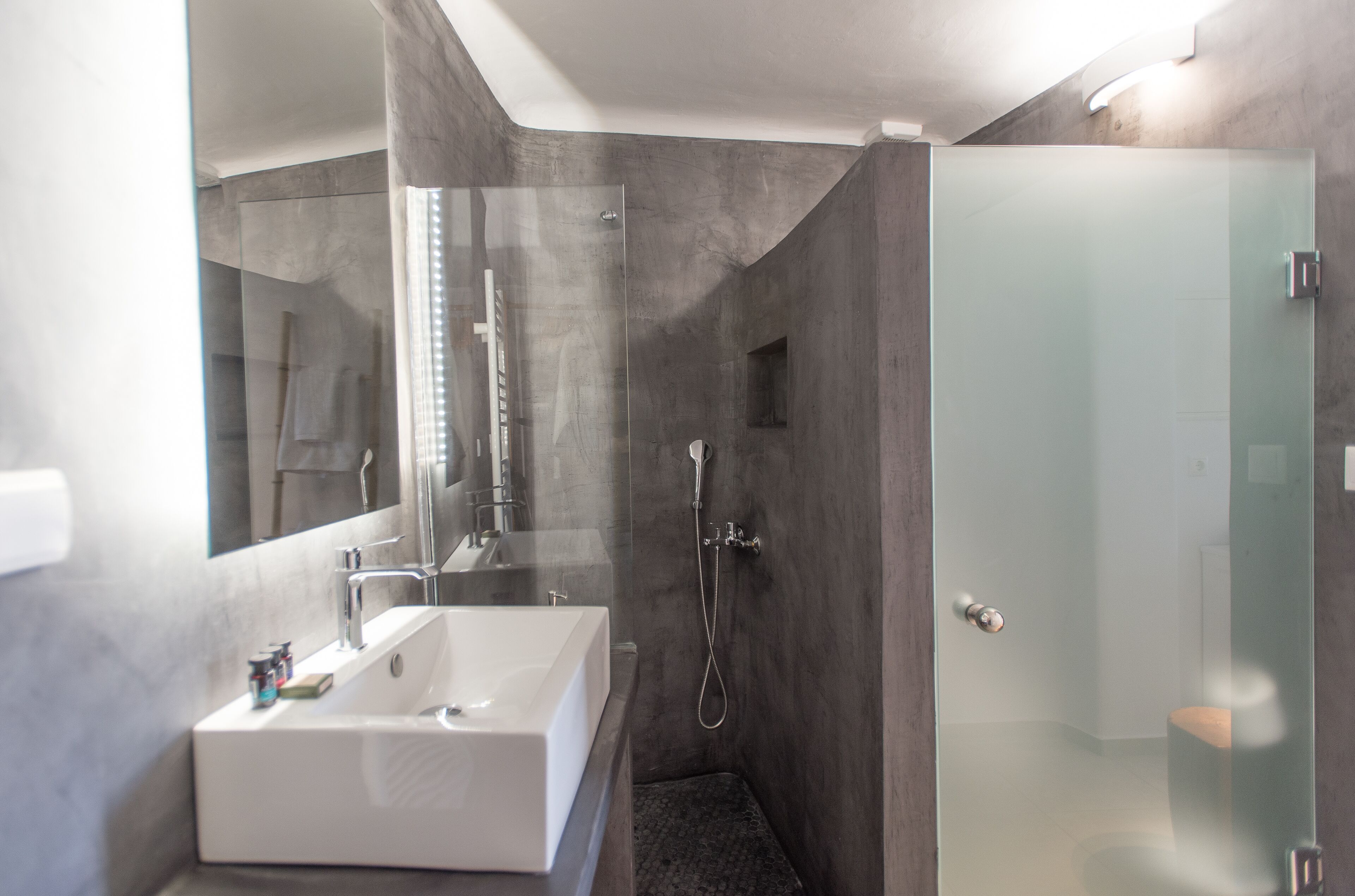 Ein modernes Badezimmer mit einer großen weißen Badewanne, einer in Glas abgeschirmten Dusche und einem Spiegel, der den Raum widerspiegelt.