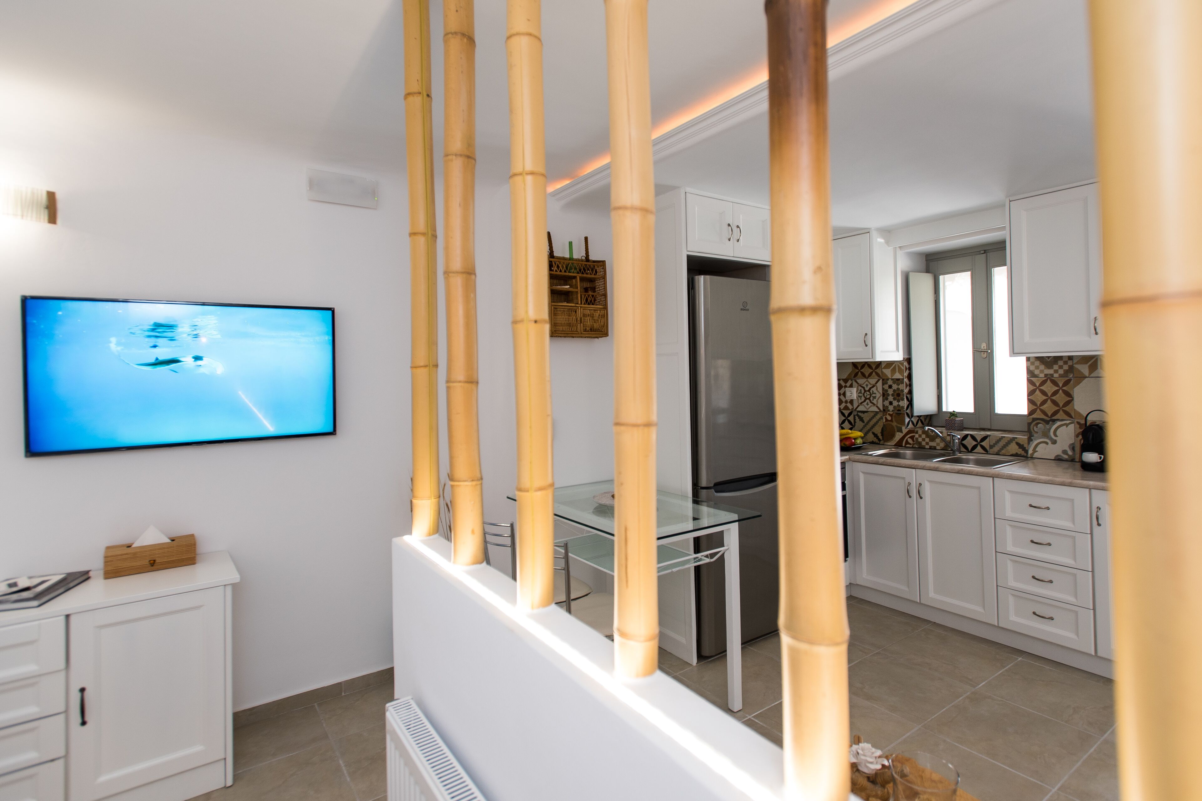A modern kitchen with white cabinets, a stainless steel refrigerator, and a glass-top table.