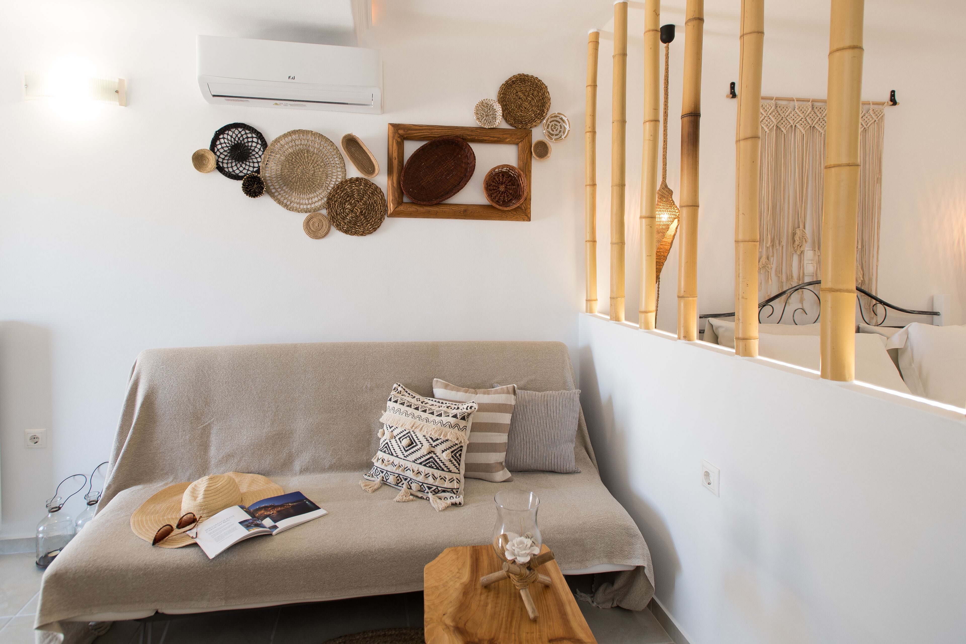 A cozy living room with a beige sofa, patterned cushions, a wooden coffee table, and a wall decorated with woven baskets and a framed picture.