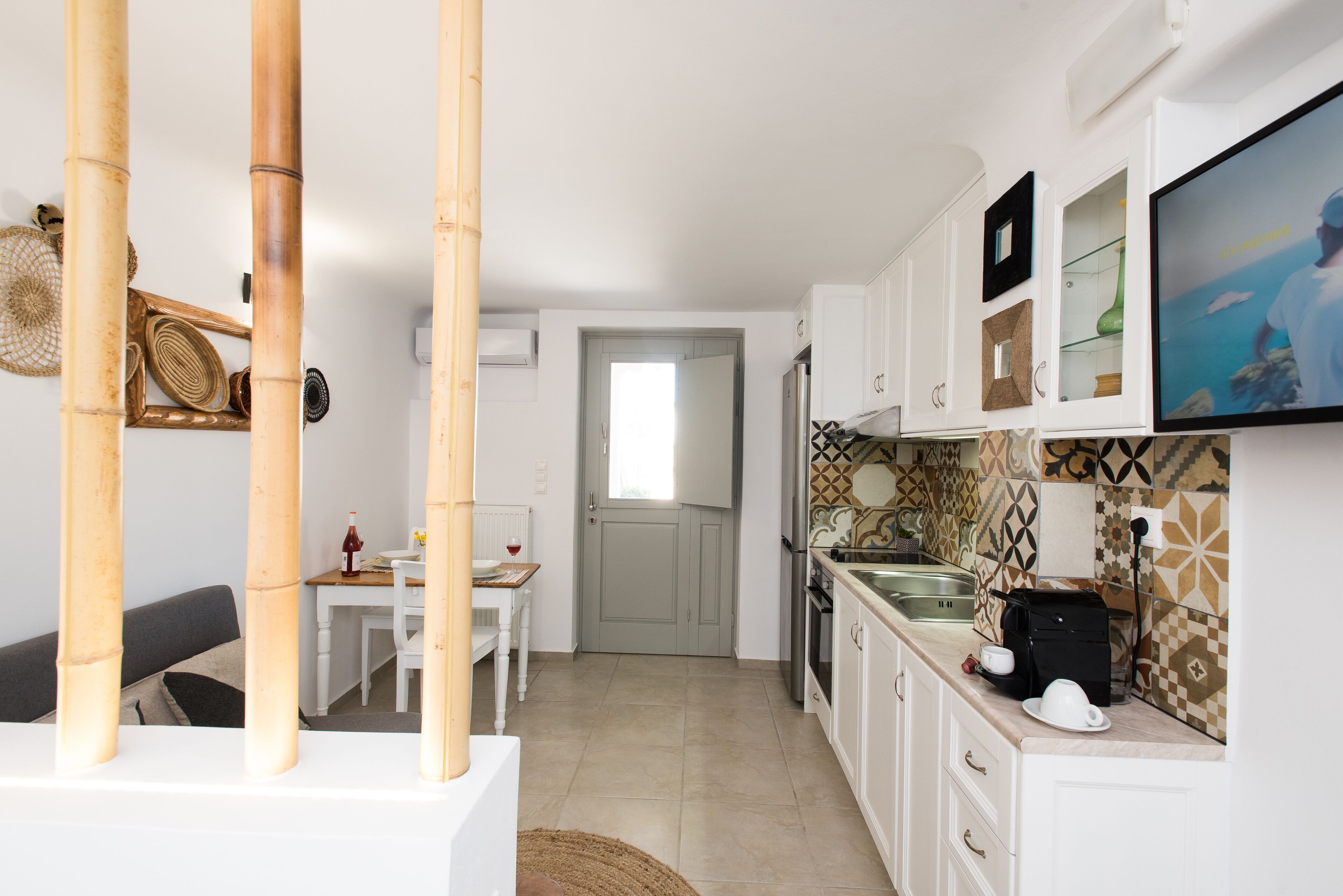 A modern kitchen with white cabinets, a built-in oven, and a large window.
