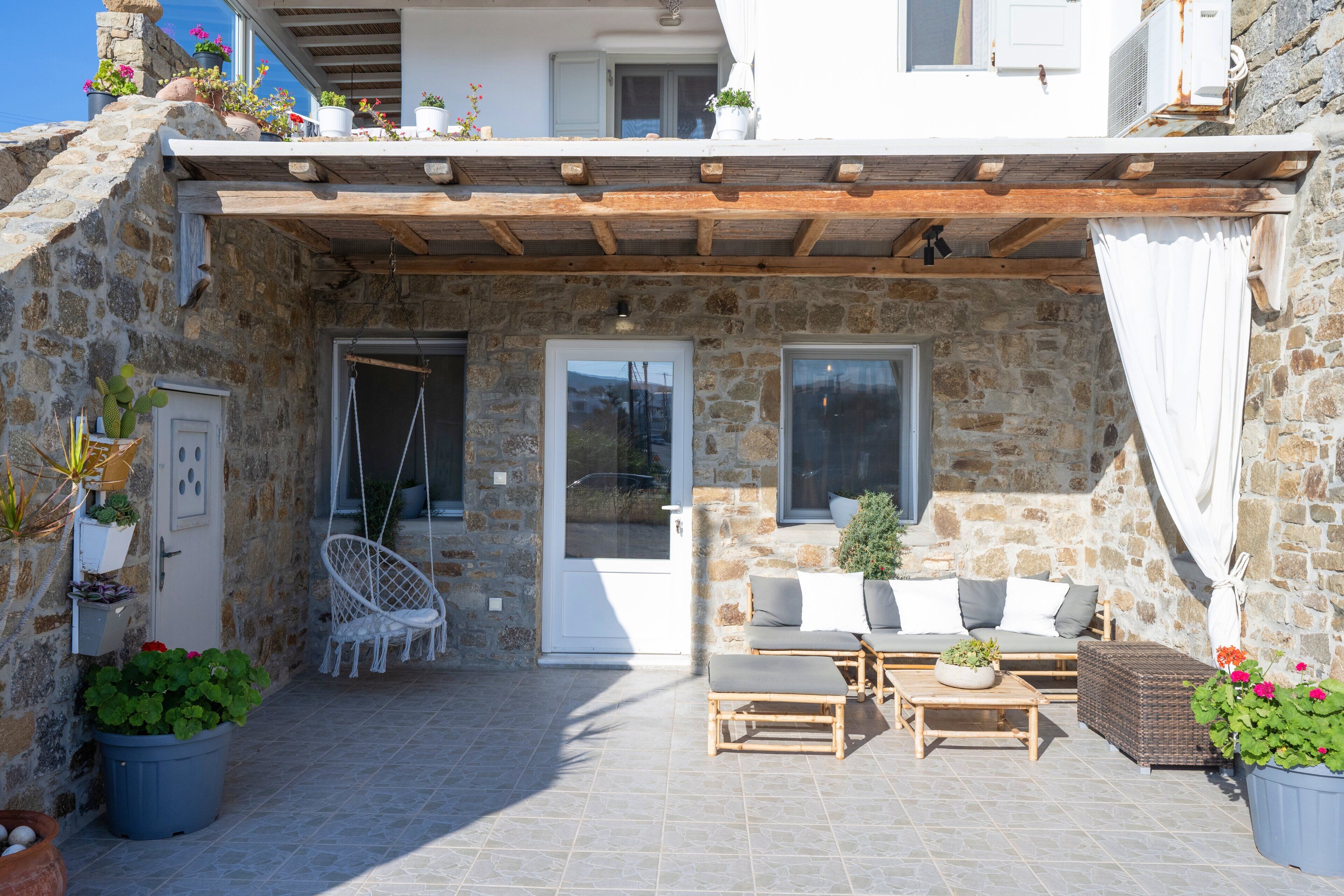 A stone building with a covered patio, outdoor seating, and potted plants.