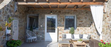 A stone building with a covered patio, outdoor seating, and potted plants.