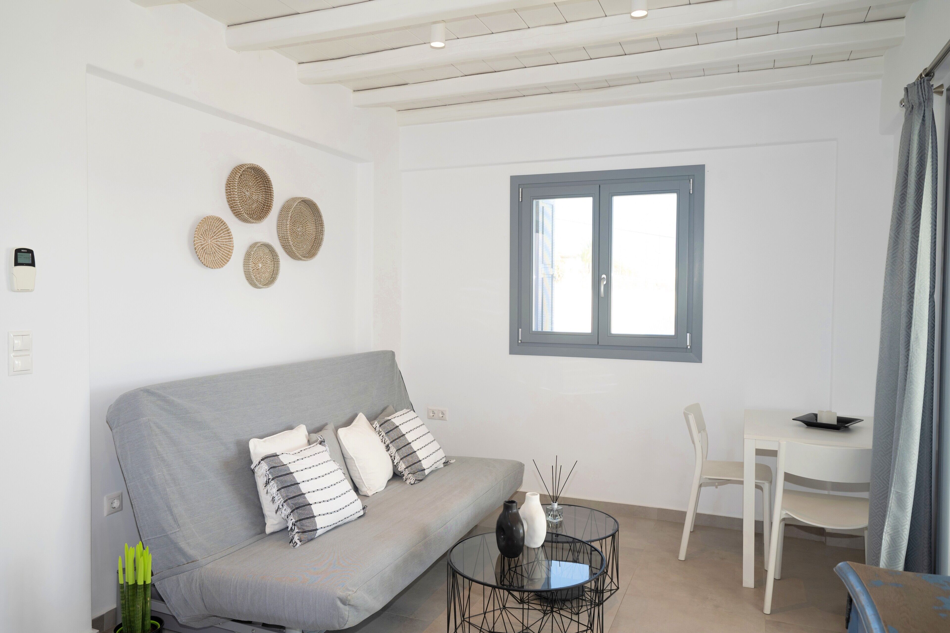 A modern living room with a grey sofa, a round coffee table, and a dining table with chairs.