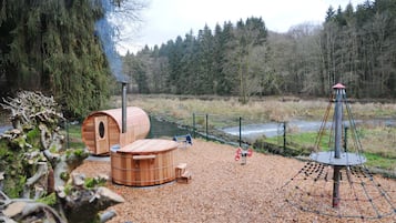 A sauna area with wooden cabins and a steam generator, surrounded by a forested landscape.
