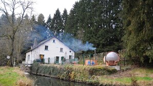 Een wit huis met een kleine tuin en een waterpartij ervoor.