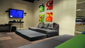 Een woonkamer met een televisie, een bank en kleurrijke kunstwerken aan de muur.