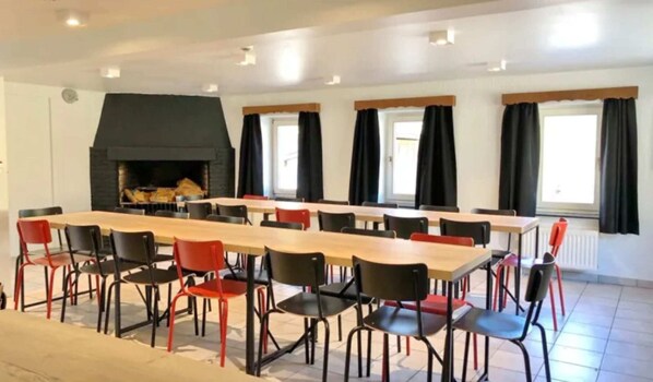 A conference room with a long table and chairs, a fireplace, and windows with curtains. - Watermill in Herbeumont With Sauna & Hot Tub (Herbeumont)