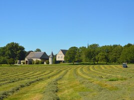 Paisaje rural con un extenso campo, una construcción de piedra y una iglesia al fondo.