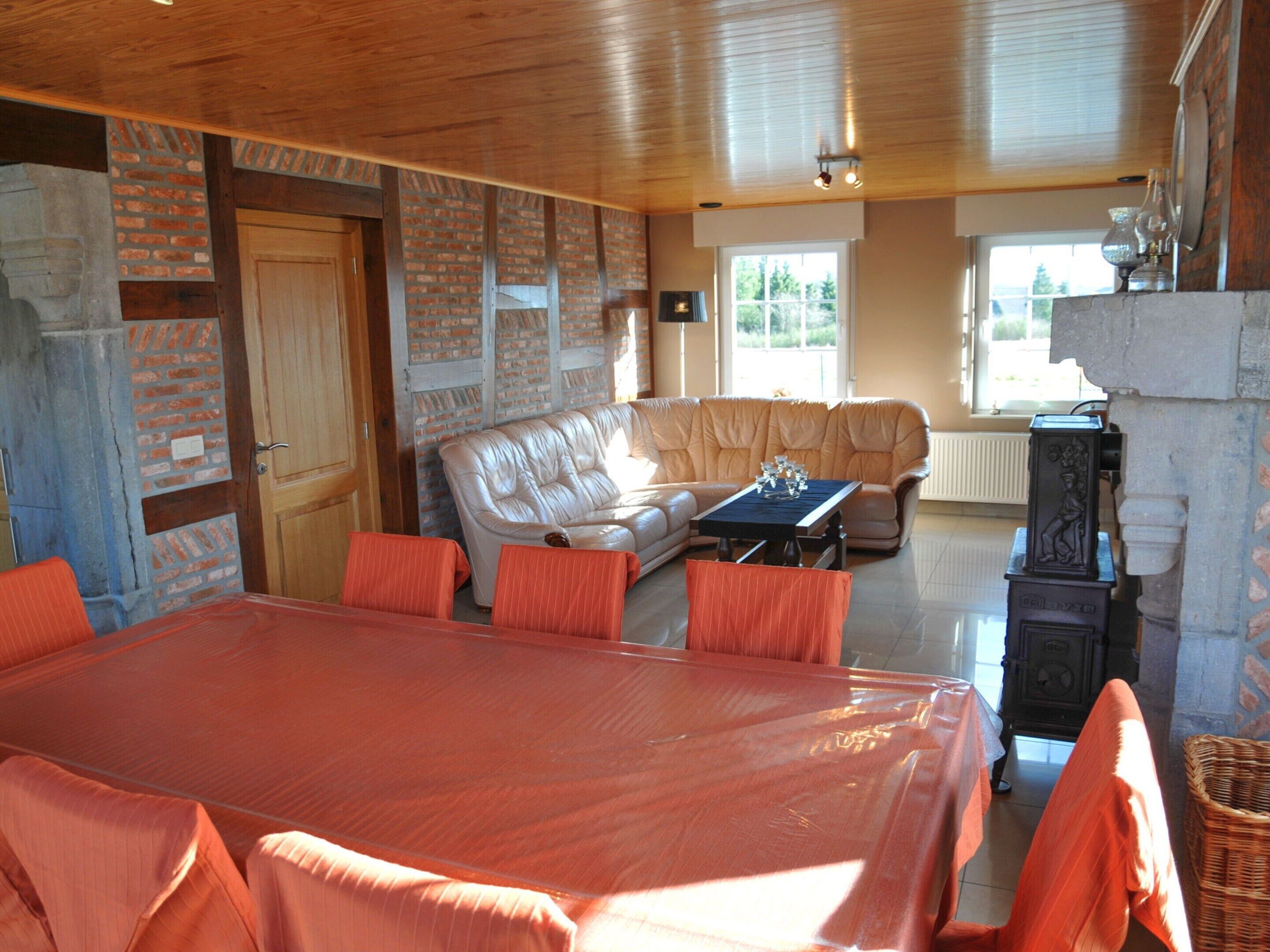 A cozy living room with a large wooden dining table, leather sofa, and a fireplace.