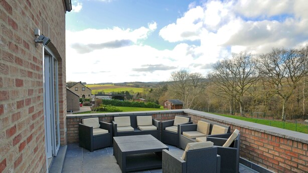 An outdoor patio with wicker furniture and a brick wall. - Holiday Home in Ardennes With Bubble Bath (Somme-Leuze)