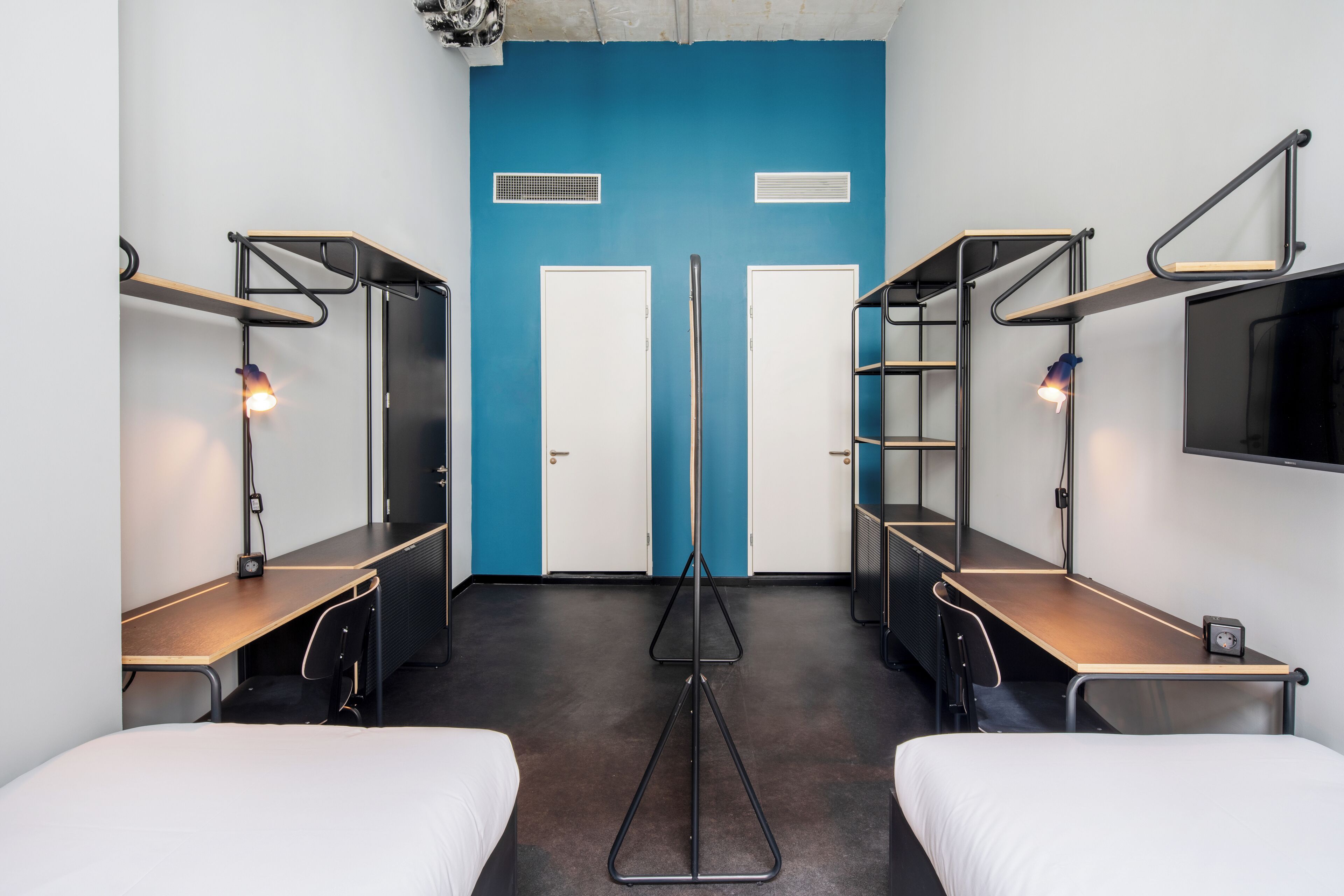 Une chambre d’hôtel moderne avec des lits superposés, un bureau et une télévision.
