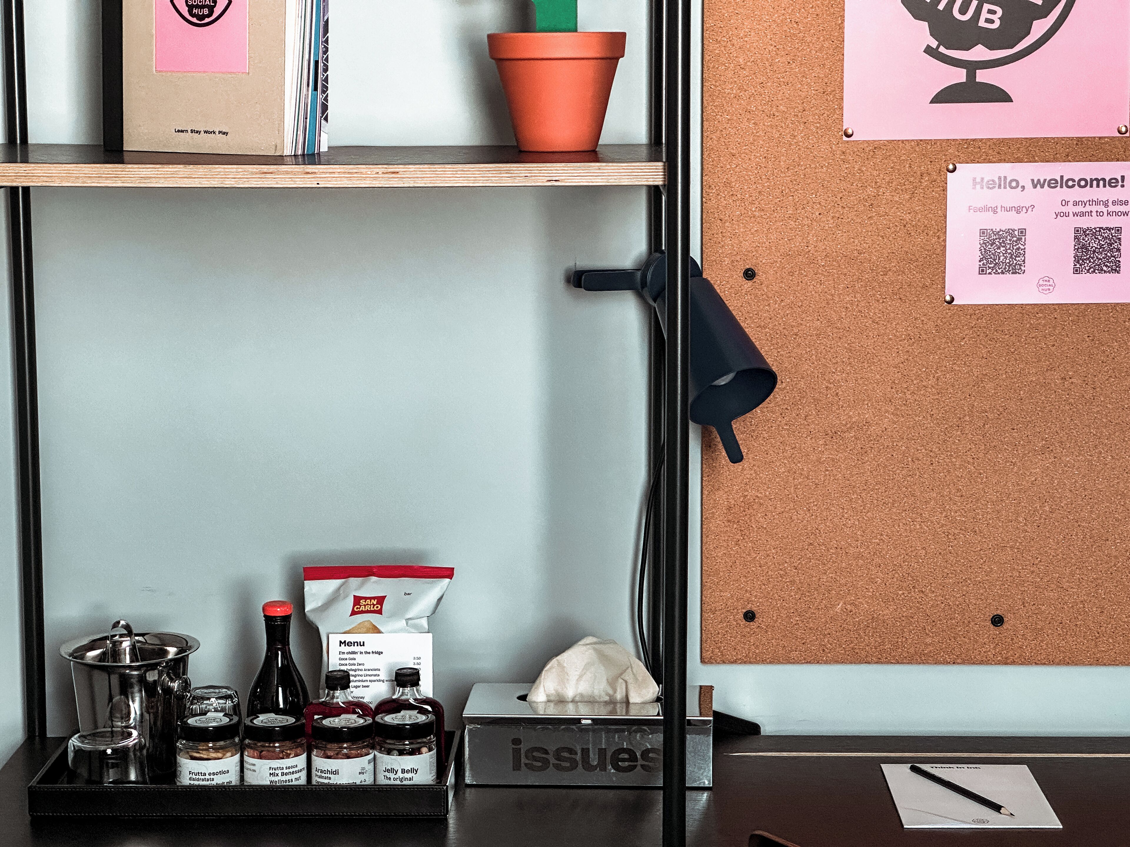 A corkboard with a welcome sign, a tray with condiments, and a box labeled 'issues'.