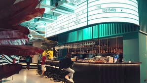 Un espace bar doté d’un comptoir incurvé, de sièges et d’une enseigne sur laquelle on peut lire « Ice Baby ».