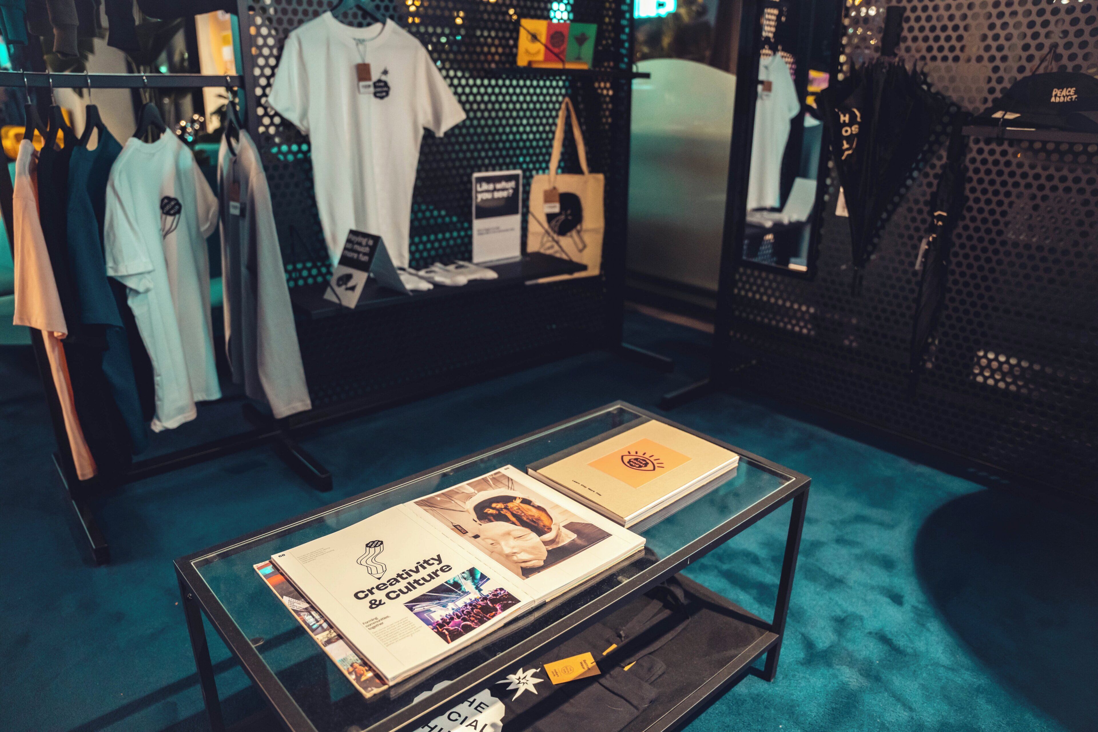 Une exposition de vêtements et une table en verre sur laquelle sont disposées des brochures.