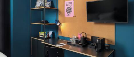 Quarto moderno com escrivaninha, cadeira, estantes, TV e um painel de cortiça com um bilhete.