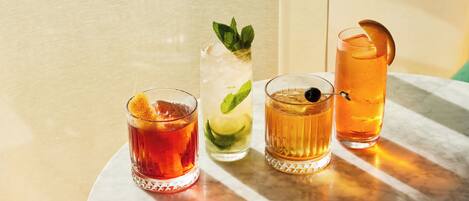 Quatre verres remplis de boissons sur une table en marbre.