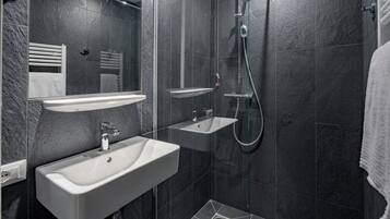Een moderne badkamer met een wastafel, spiegel en douche.