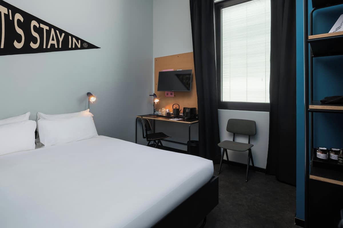 Une chambre d’hôtel équipée d’un lit, d’un bureau, d’une chaise, d’une télévision et d’une bibliothèque.