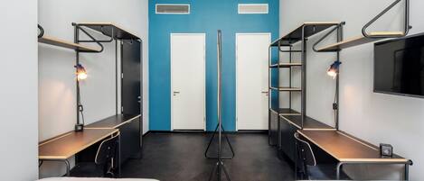 A room with bunk beds, a desk, a chair, a TV, and a blue accent wall.