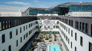 Un espace piscine aménagé sur le toit, offrant une vue dégagée sur l’architecture du bâtiment, notamment sa façade moderne en verre et une fresque murale aux motifs originaux.