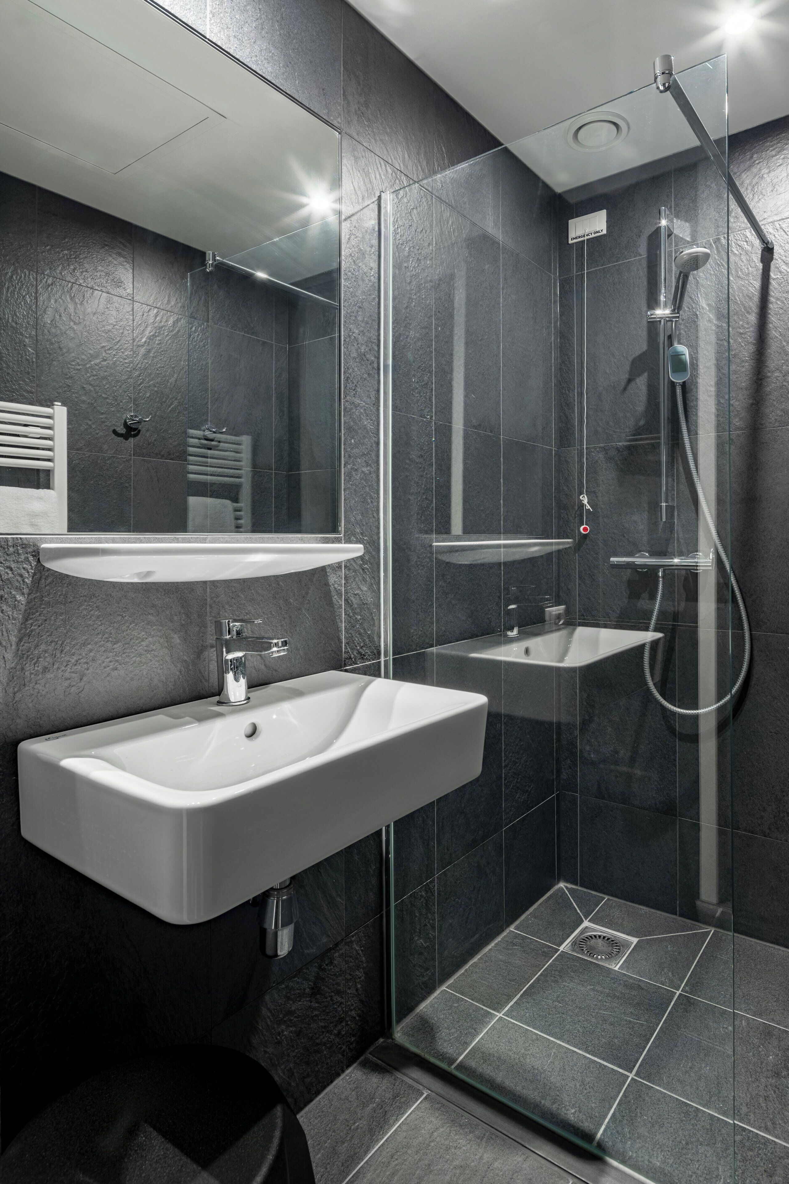 Un baño moderno con ducha de vidrio, lavamanos y espejo.