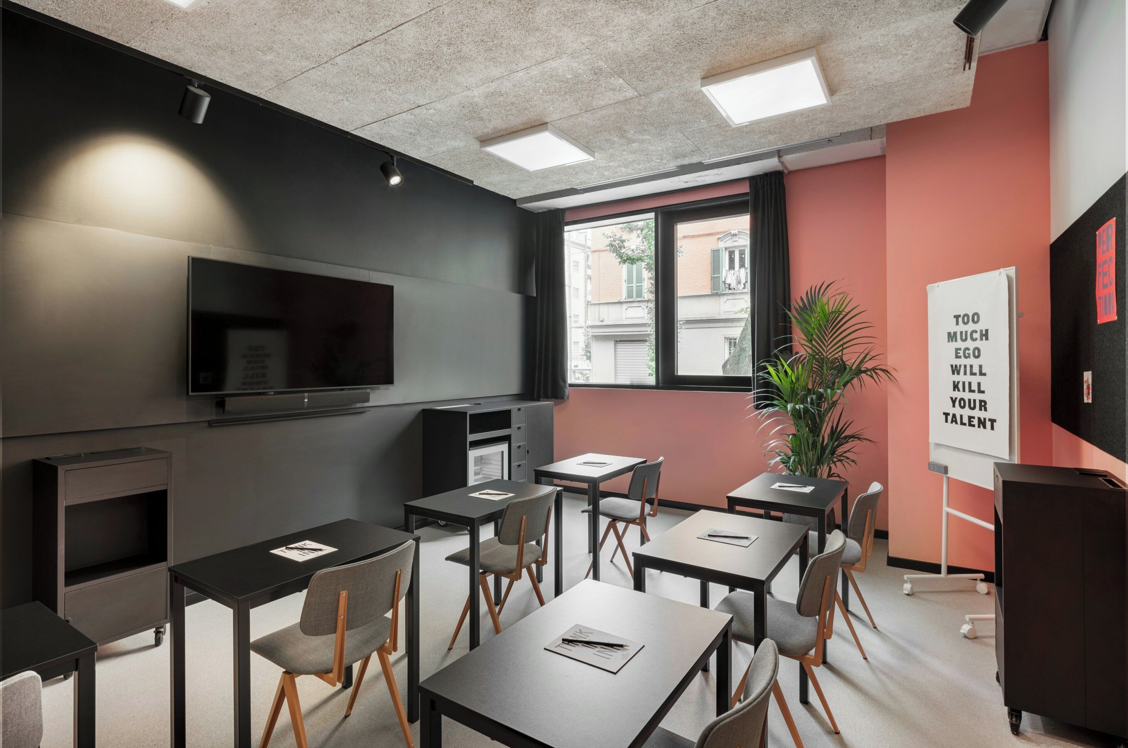 A conference room with tables, chairs, a television, a potted plant, and motivational posters.